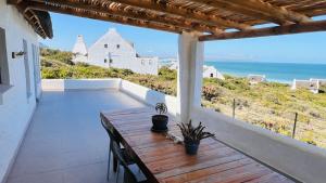 a balcony with a wooden table and a view of the ocean at Kleinbos Beach Villa in Boggomsbaai