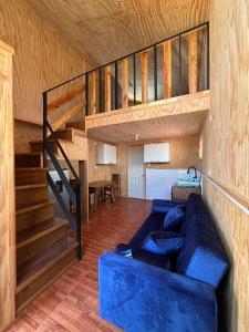 Una sala de estar con un sofá azul y una escalera. en Tiny House in Valdivia, en Valdivia