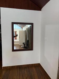 einen Spiegel an einer Wand mit einem Stuhl in einem Zimmer in der Unterkunft Rose Villa Homestay in Avathi