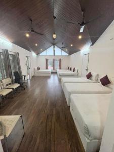 ein großes Zimmer mit zwei Betten, Tischen und Stühlen in der Unterkunft Rose Villa Homestay in Avathi