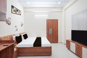 a bedroom with a bed and a flat screen tv at Hotel O Radha Residency in Dahmi