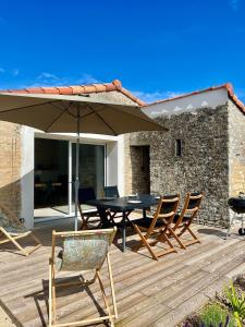 un patio con tavolo, sedie e ombrellone di La Longère des Surfeurs - Plage Bud Bud - Calme a Longeville-sur-Mer