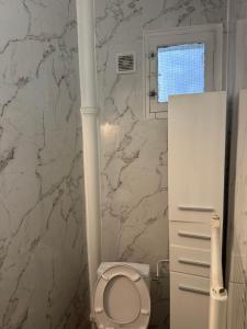 a bathroom with a toilet and a marble wall at Appartement in Montreuil