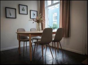 a dining room table with chairs and a vase of flowers at Cheap Room in The Heart of Brosundet in Ålesund