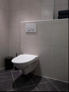 a bathroom with a toilet in a tiled wall at Cheap Room in The Heart of Brosundet in Ålesund