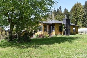 a yellow house with a tree in a field at Farmhouse Cabin in the Redwoods in Eureka