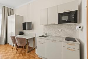 a kitchen with white cabinets and a table and a microwave at Near Schönbrunn I 1 Min to U6 Niederhofstraße in Vienna +100 photos