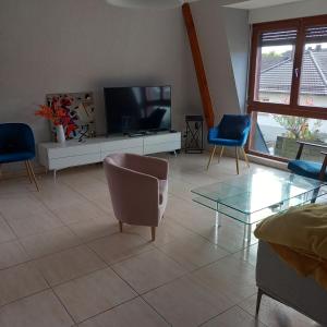 a living room with a tv and two chairs and a table at Les pervenches in Illkirch-Graffenstaden