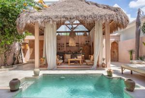 a swimming pool with a straw umbrella and a house at Villa Pinkaboo - Gorgeous and Luxury One-Bedroom Villa in the Heart of Canggu in Canggu