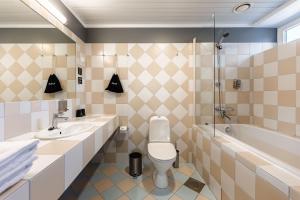 a bathroom with a toilet and a sink and a tub at Hotel NOSPA in Kuressaare +78 photos