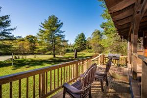 - une terrasse couverte avec 2 chaises et une table dans l'établissement Two Bedroom Log Cabin, à Unionville