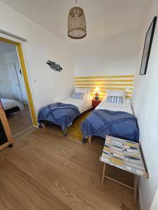 a room with two beds and a table in it at Joli cocon vue mer exceptionnelle proche plages in Plouguerneau