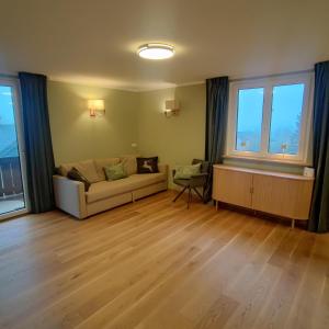 salon z kanapą i dwoma oknami w obiekcie Alpenperle w mieście Sankt Johann im Pongau