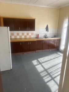 Una cocina vacía con gabinetes marrones y un fregadero. en The Cargo Club Guesthouse, en Ventersburg