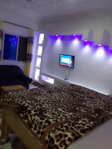 a bedroom with a leopard print bed and a flat screen tv at LMD Apartments in Kololi