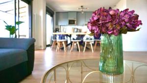 a vase of purple flowers sitting on a glass table at Villa Los Ángeles - El Espinar in Los Ángeles de San Rafael