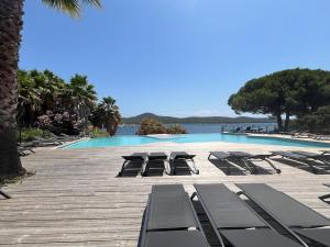 un groupe de chaises longues et une piscine dans l'établissement amazing sea front apartment, à Pianottoli-Caldarello
