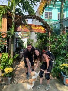 a man and a woman petting a dog in a garden at Tam Coc My Tho Homestay in Vũ Lâm