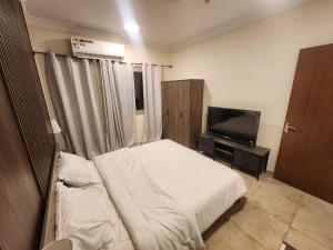 a bedroom with a bed and a flat screen tv at شقق مفروشة الهتون تاور شارع الحج in Miná
