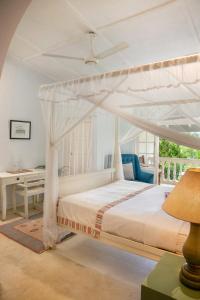 1 dormitorio con cama blanca con dosel y escritorio en Ashburnham Estate, en Elkaduwa