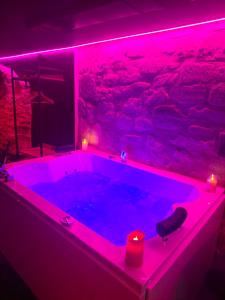 a jacuzzi tub with pink lights in a room at La Cachette Secrète - Maison romantique avec Balnéo et Sauna Privatif à Caen en Normandie in Caen