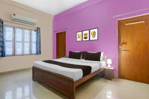 a bedroom with a bed with a purple wall at Hotel O BABA GUEST HOUSE in Shivāpur