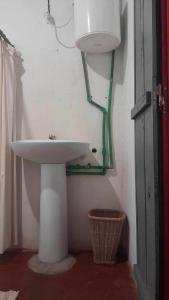 une salle de bain avec un lavabo blanc et des tuyaux verts dans l'établissement Petite Maison Sainte-Marie, Madagascar, sur l'île Sainte-Marie