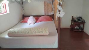 une chambre avec un lit avec des oreillers roses dans l'établissement Petite Maison Sainte-Marie, Madagascar, sur l'île Sainte-Marie
