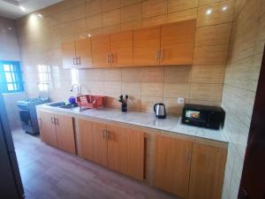 a kitchen with wooden cabinets and a microwave at Fleur d'hibiscus in Cotonou +4 photos