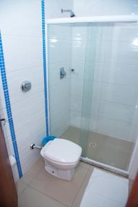 a bathroom with a toilet and a glass shower at Hotel Suiça Faber in Balneário Camboriú