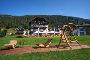 a playground with chairs and a slide in front of a building at SeeHotel & SeeApartments Kärntnerhof- direkt am See! in Weissensee