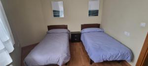 two beds in a room with purple pillows at Piso con piscina entre 2 playas - Floor with pool between 2 beaches in O Porto de Espasante