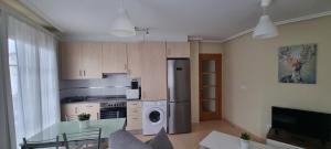 a kitchen with a refrigerator and a table in a room at Piso con piscina entre 2 playas - Floor with pool between 2 beaches in O Porto de Espasante