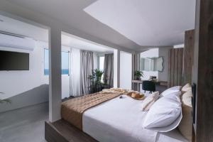 una habitación con una cama grande con sábanas y almohadas blancas en Alcyone Studios and Apartments, en Heraclión