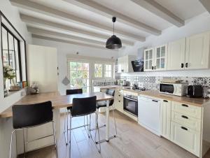 Una cocina con gabinetes blancos y una mesa y sillas. en Maison Magnolia proche de la plage à Sainte Marie de Ré, en Sainte-Marie-de-Ré