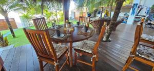 a wooden table and chairs on a deck with palm trees at Upwind Villas Boutique - Praia de Maceió - Camocim - CE in Maceio