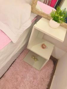 a white nightstand with two shelves and a pink rug at Quartos Privados em casa Mobiliada in Londrina +8 photos
