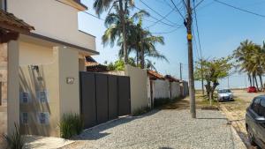 a house with a black gate and palm trees at Studios Piscina Privativa Pé na areia in Peruíbe