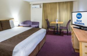 a hotel room with a bed, desk, chair and a television at Hospitality Geraldton, SureStay by Best Western in Geraldton