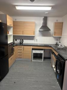 una cocina con armarios de madera y un aparato negro en One Bedroom Apartment in Greenwich Peninsula, en Moffat