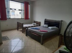 Un dormitorio con una cama y un sofá y una ventana. en Pousada Central, en Guaratinguetá