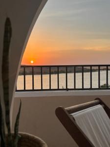 a view of the ocean from a balcony with a sunset at Golden Sun House I in Abu Simbel