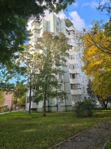 Un edificio blanco con árboles delante. en VIP Квартира в центре Бендер улица Кирова 36, en Bender