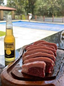 een stuk vlees op een snijplank naast een fles bier bij CasaBela in Juatuba +13 foto's