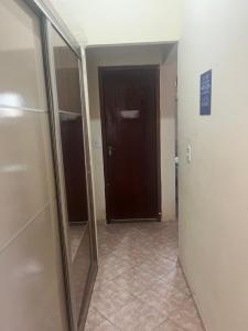 a hallway with a mirror and a brown door at Via sol casa 2 térreo in Rio das Ostras +1 photo