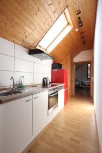 een keuken met witte kasten en een rode koelkast bij Seeblick Hotel-Ferienhaus- Obermaubach in Kreuzau +16 foto's