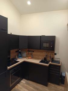 a kitchen with black cabinets and a microwave at Appartement 6 personnes avec terrasse in Montbrison