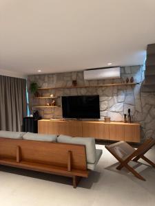 Una sala de estar con un sofá y un televisor de pantalla plana. en Triplex Nalu - Sofisticação na Rota Ecológica de Milagres, en Porto de Pedras