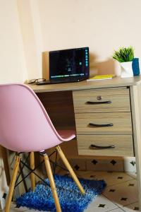 un escritorio con una silla rosa y una computadora encima. en Haus Cossie, en Machakos