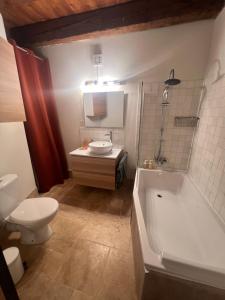 a bathroom with a tub and a toilet and a sink at Appartement 6 personnes avec terrasse in Montbrison